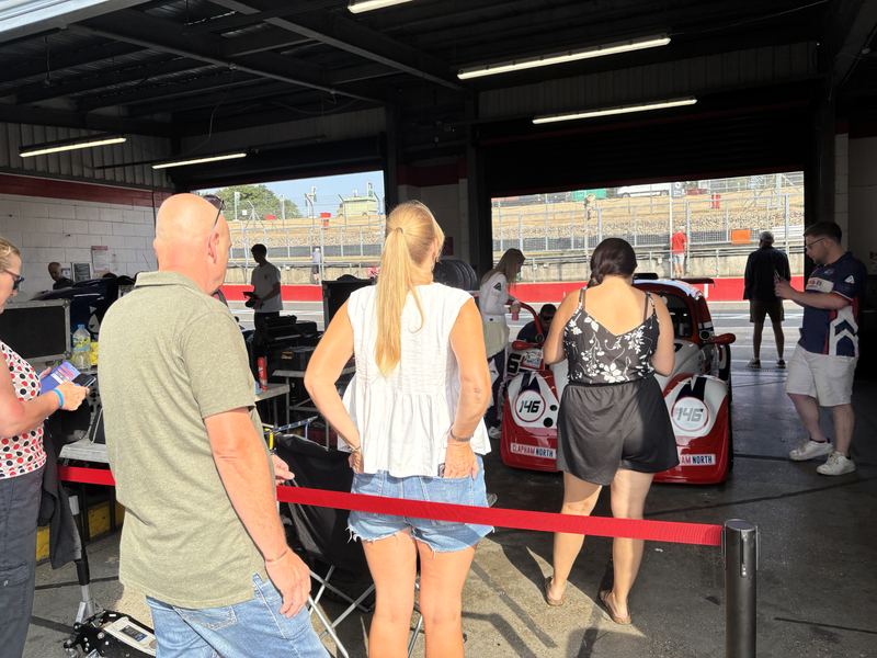 Guests in the pit garage looking at the car