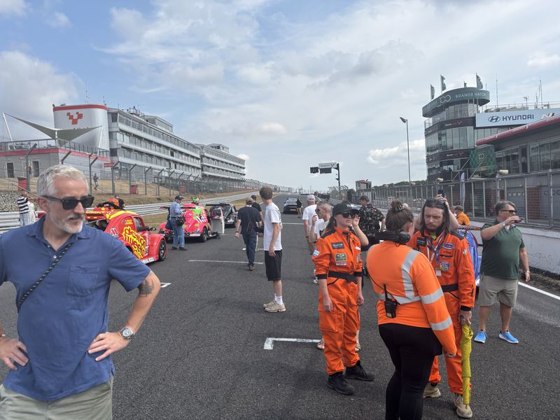 Marshals in orange and guests on the grid at Brands Hatch